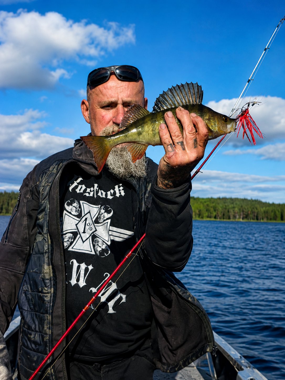Angler zeigt einen Barsch neben der Angelrute