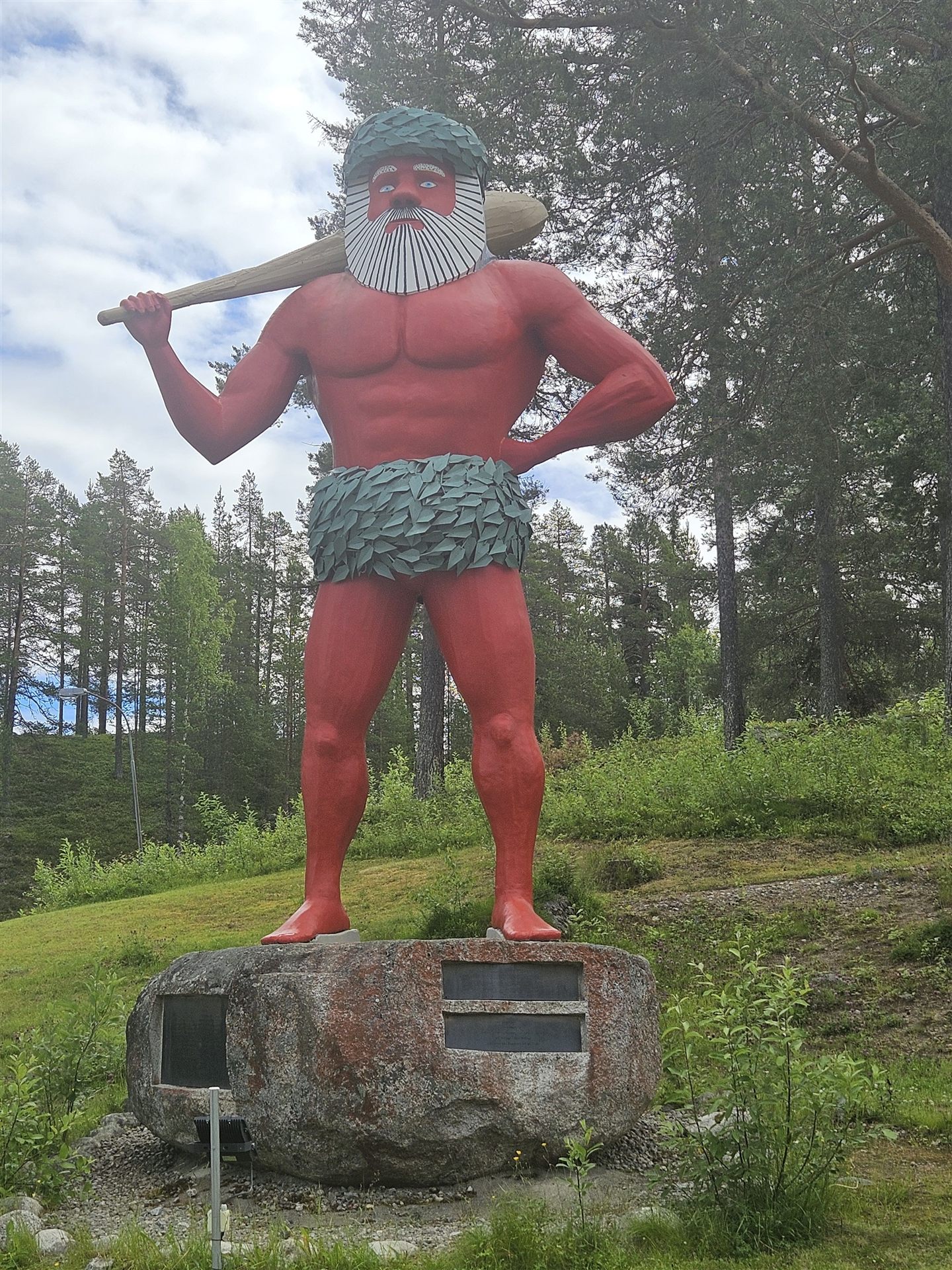 Rote Sami-Figur mit Keule in einem Waldpark