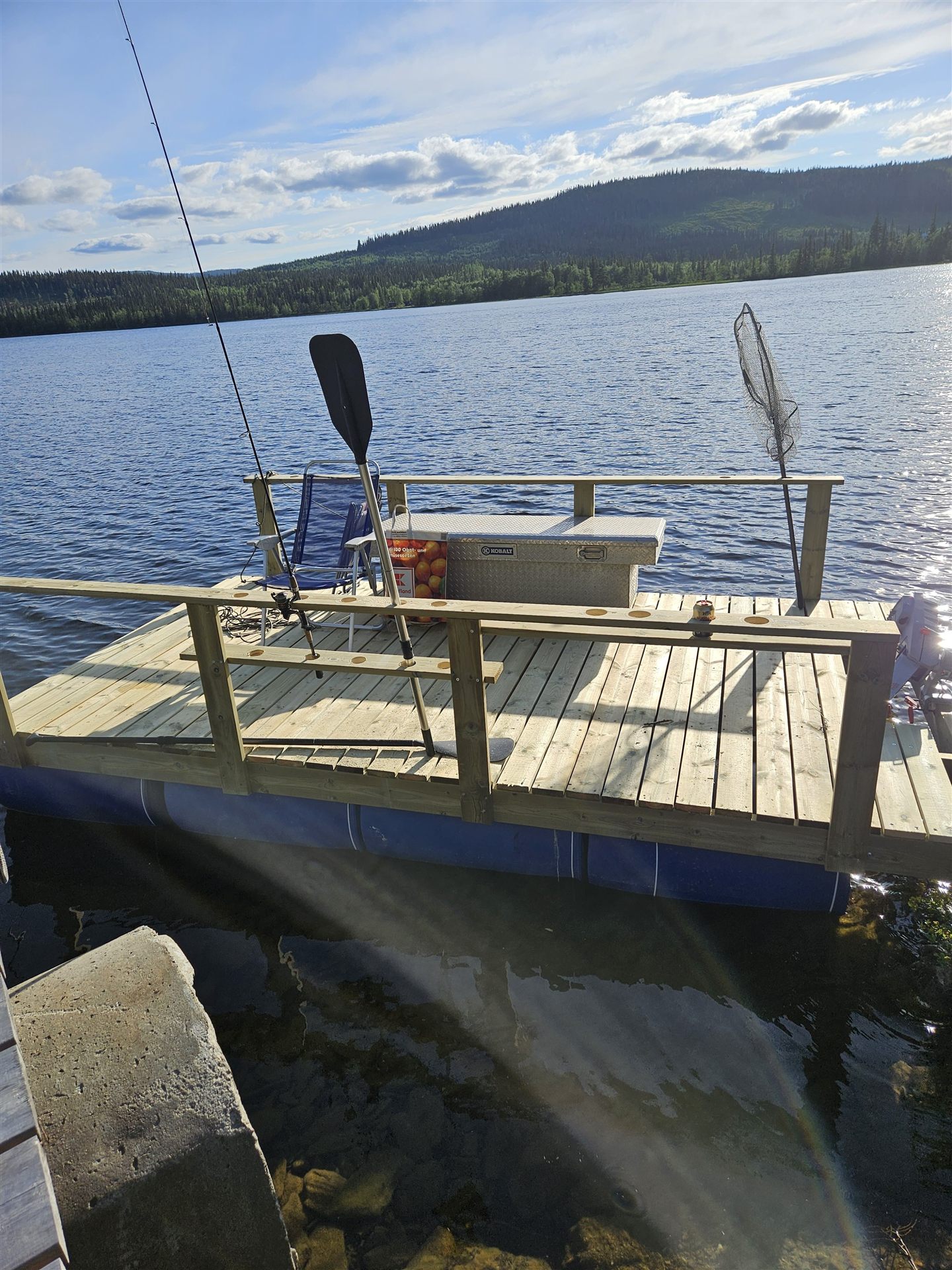 Bootssteg mit Angelausruestung und Blick ueber den See