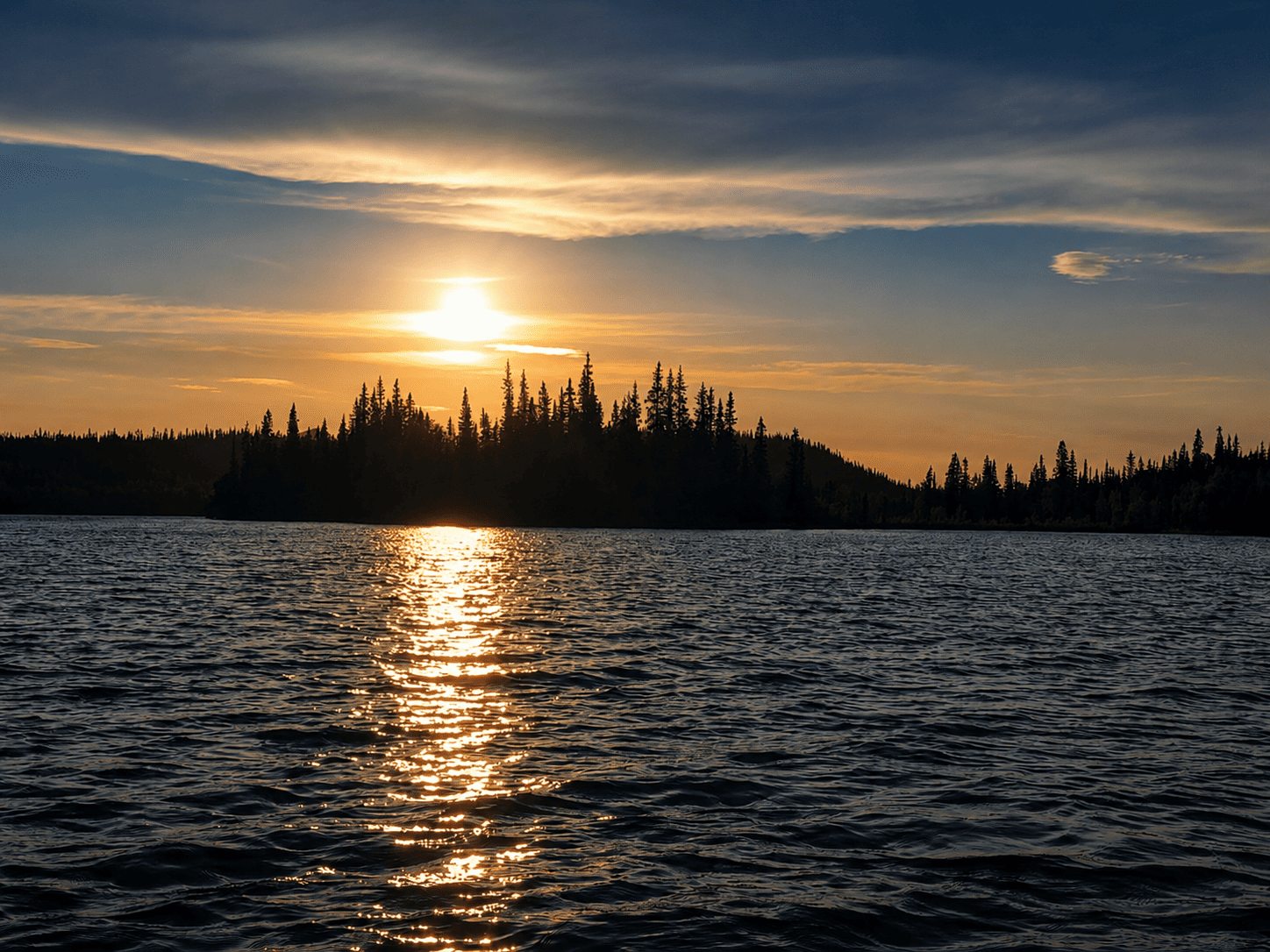 Sonnenuntergang ueber einem See mit Waldsilhouette