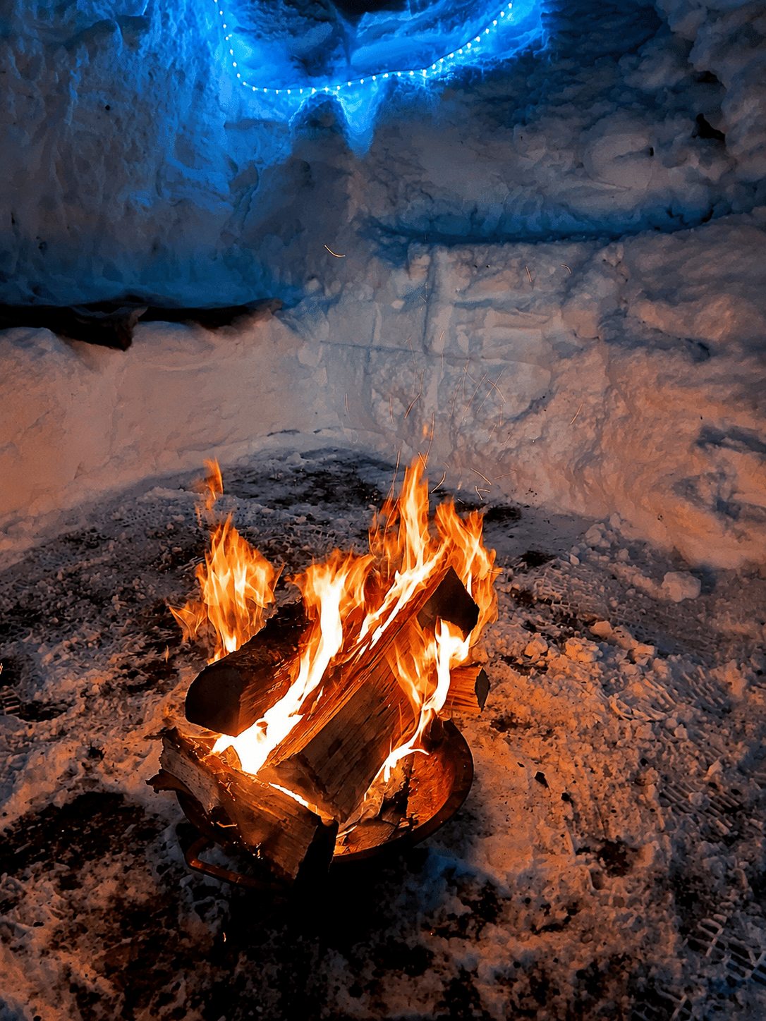 Feuerstelle in einer Schneenische mit blauem Licht