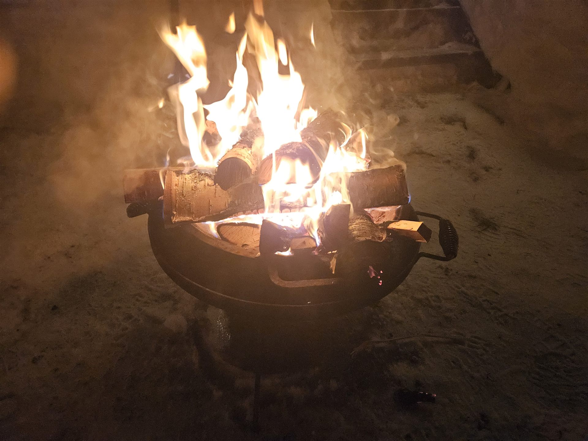 Feuerstelle mit brennendem Holz am Winterabend